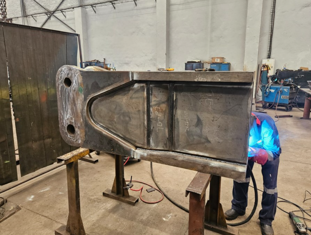 Fabricated steel component being welded in a workshop environment.
